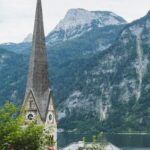 Church steeple with a mountainous backdrop in a quaint lakeside town.