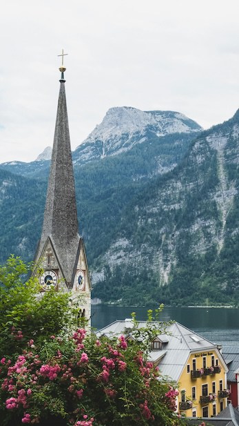 Church steeple with a mountainous backdrop in a quaint lakeside town.