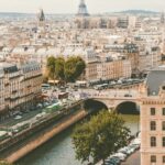 A panoramic view of paris showcasing the seine river, city buildings, and the eiffel tower in the distance.