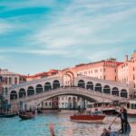 A gondolier navigating a gondola near the rialto bridge in venice, italy.