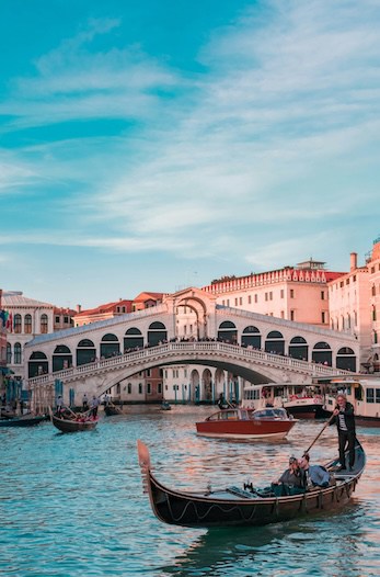 A gondolier navigating a gondola near the rialto bridge in venice, italy.