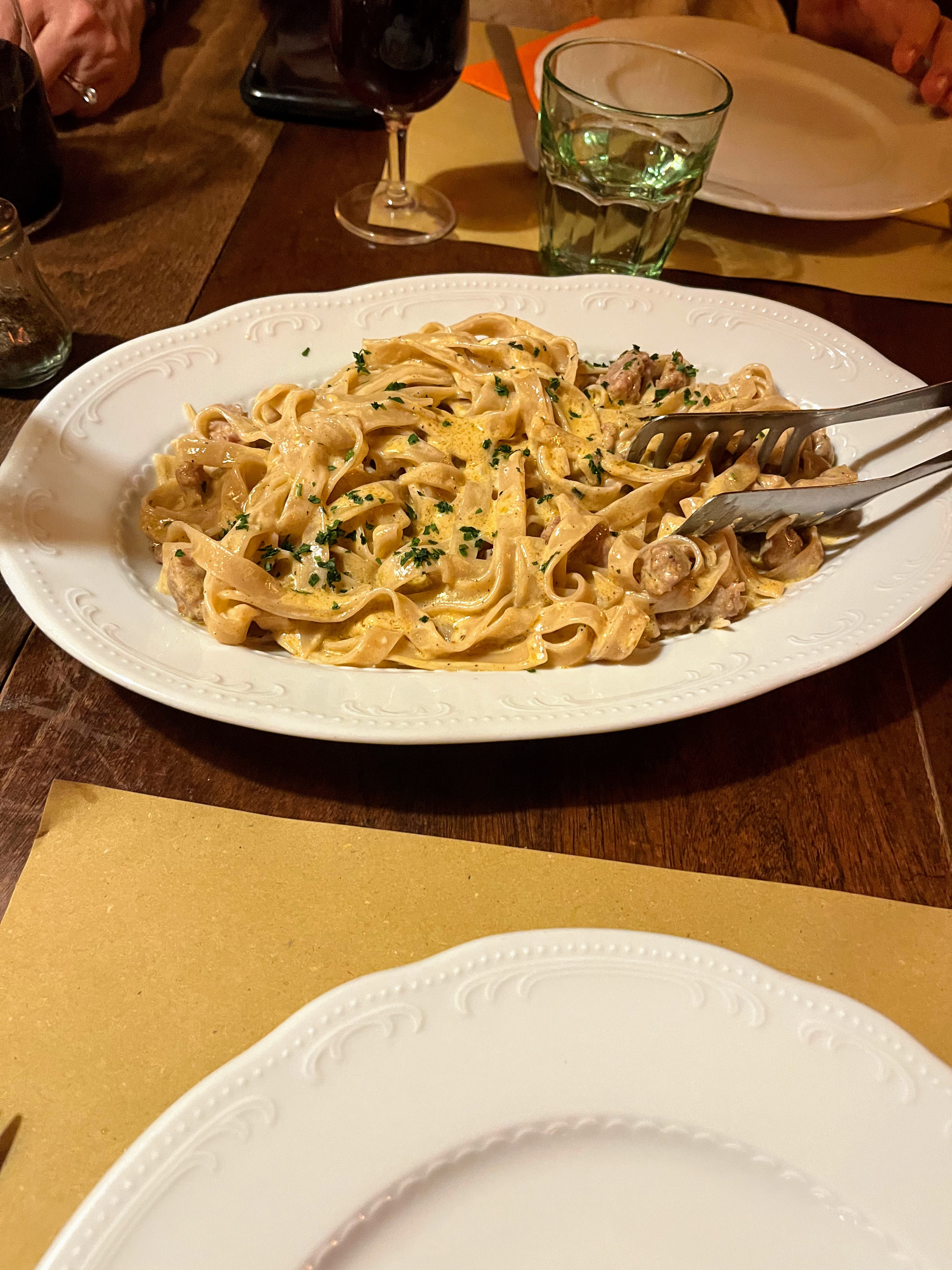 A plate of creamy pasta with a pair of tongs