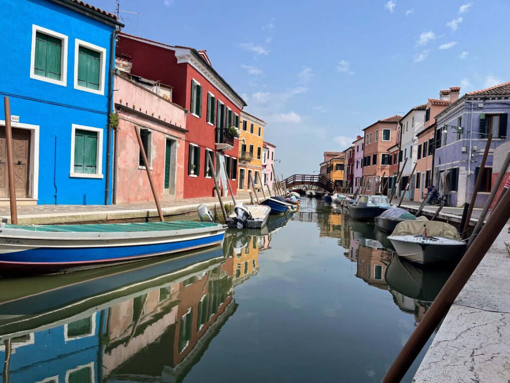 A calm canal lined with parked boats and many colorful buildings