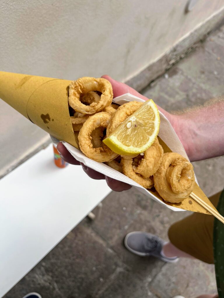 A paper code filled with rings of calamari topped with a lemon wedge 