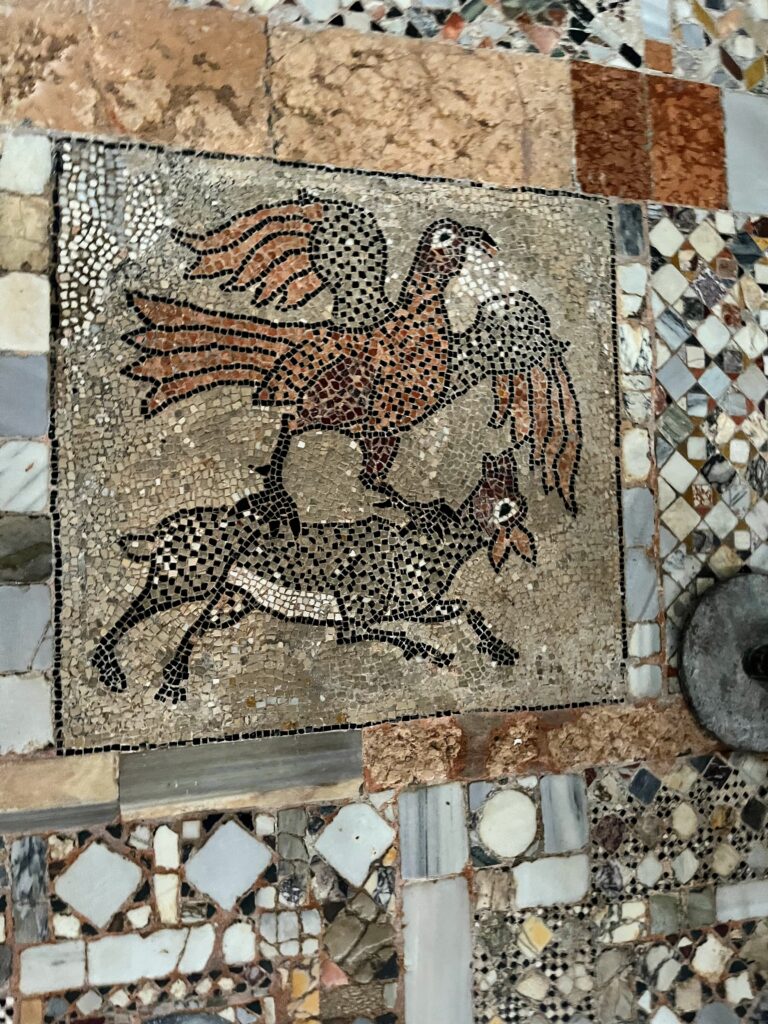 A tile mosaic of a bird attempting to carry another bird