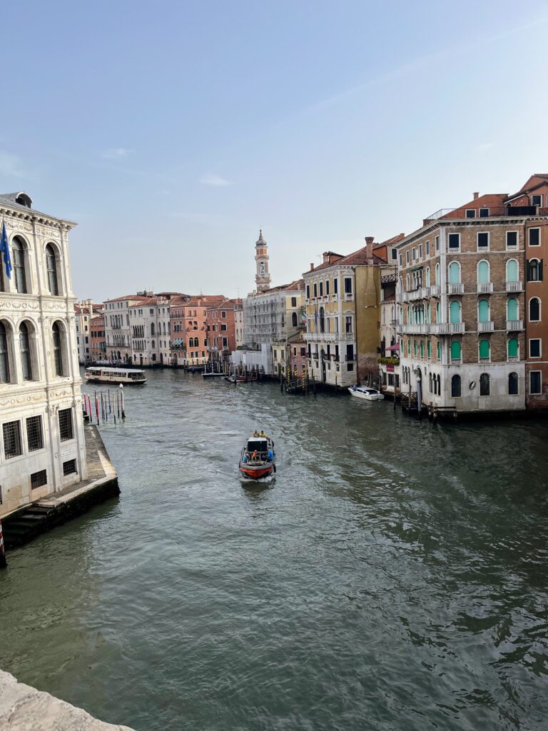 A view over a canal with historic buildings on either side and a small boat in the middle