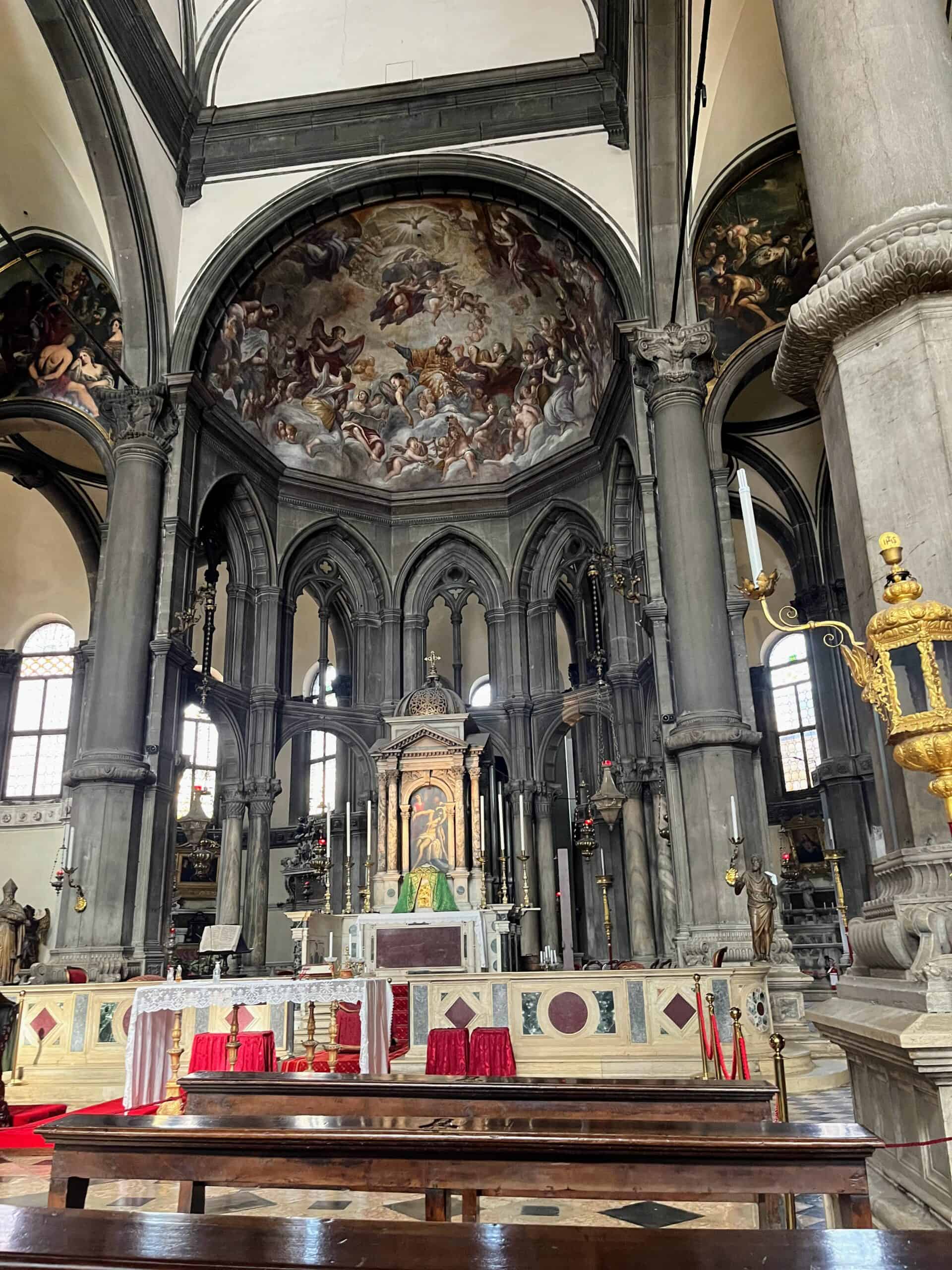 A catholic church altar with an ornate painting on the domed ceiling