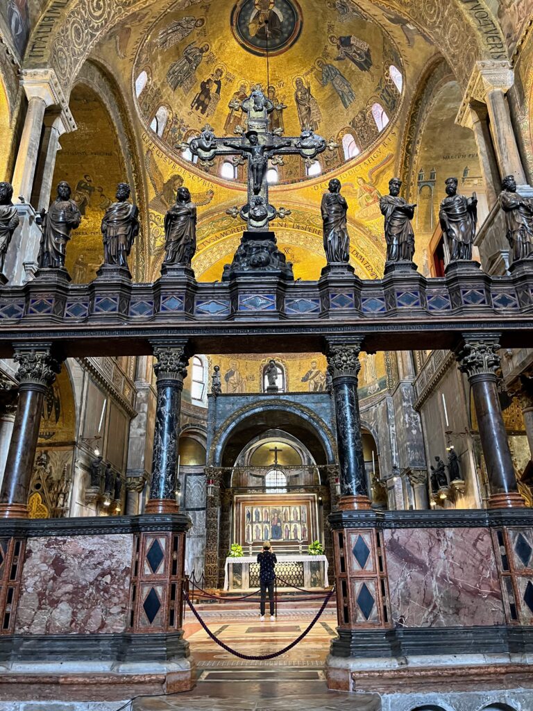 Photo of an altar with a statue of jesus on the cross with a golden ceiling in the background