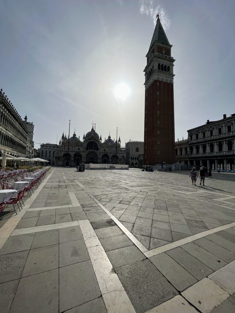 A city square with a large bell tower and ornate cathedral