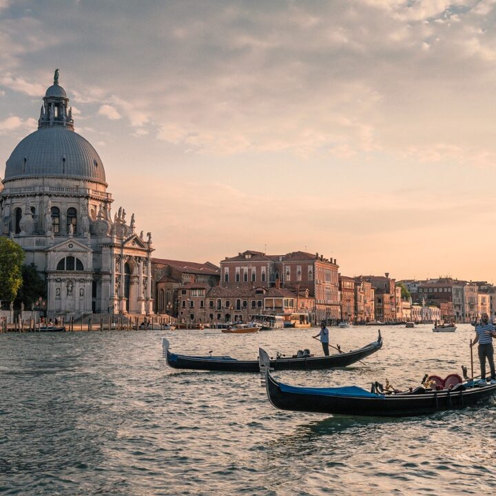 Sunset over a Venetian canal, with 2 gondoliers in the water