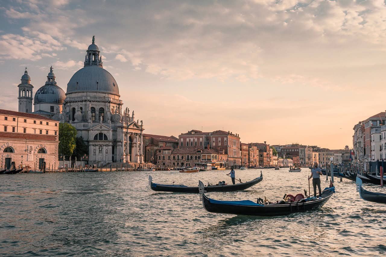 Sunset over a Venetian canal, with 2 gondoliers in the water