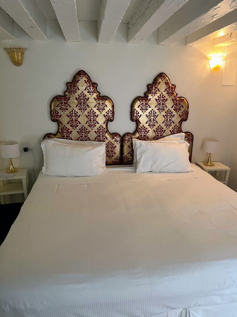 A hotel bed with two sets of pillows, nightstands, and wall-mounted lamps